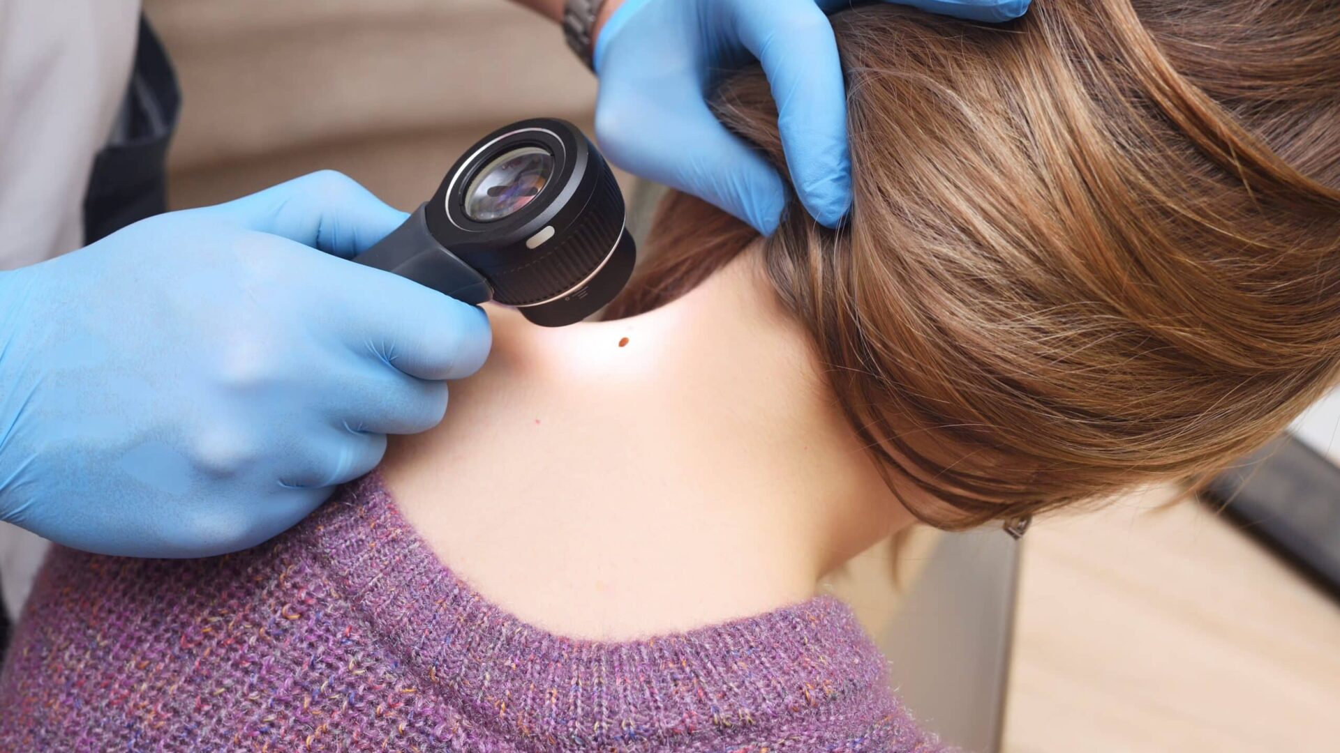 Dermatologist using dermoscopy on patient's neck skin