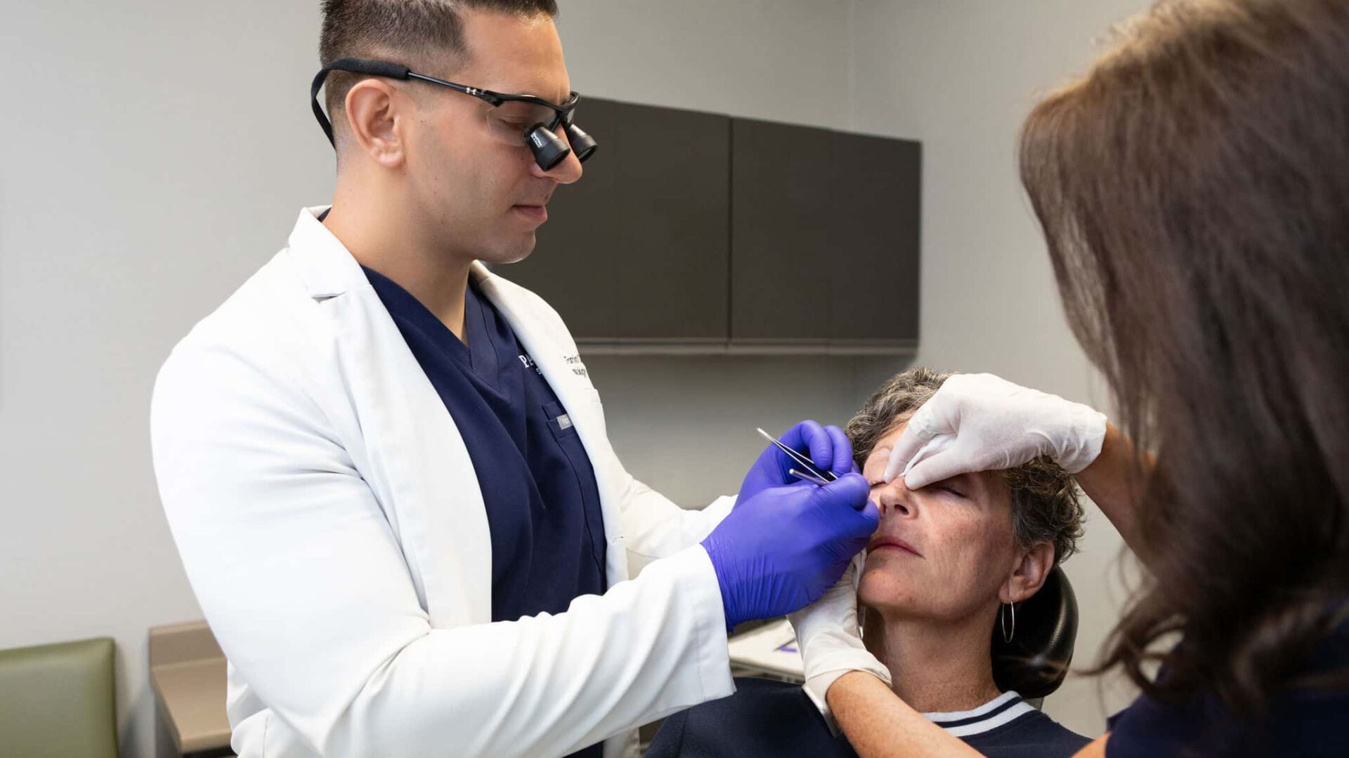 Doctor performing dermal filler procedure on patient at clinic