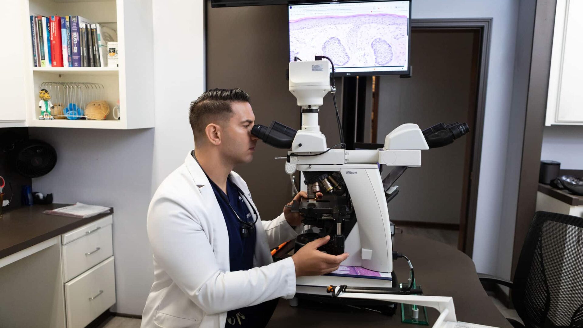 Dermatologist examining skin samples with a microscope in a clinic
