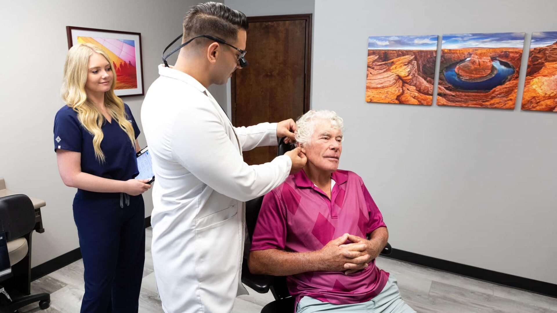 Dermatologist examining senior man's ear in clinic
