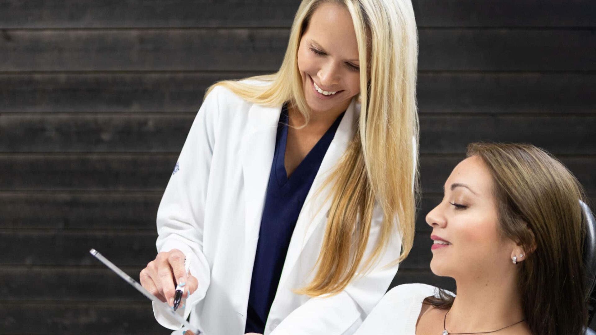 Cosmetologist demonstrating dermal filler procedure to a client