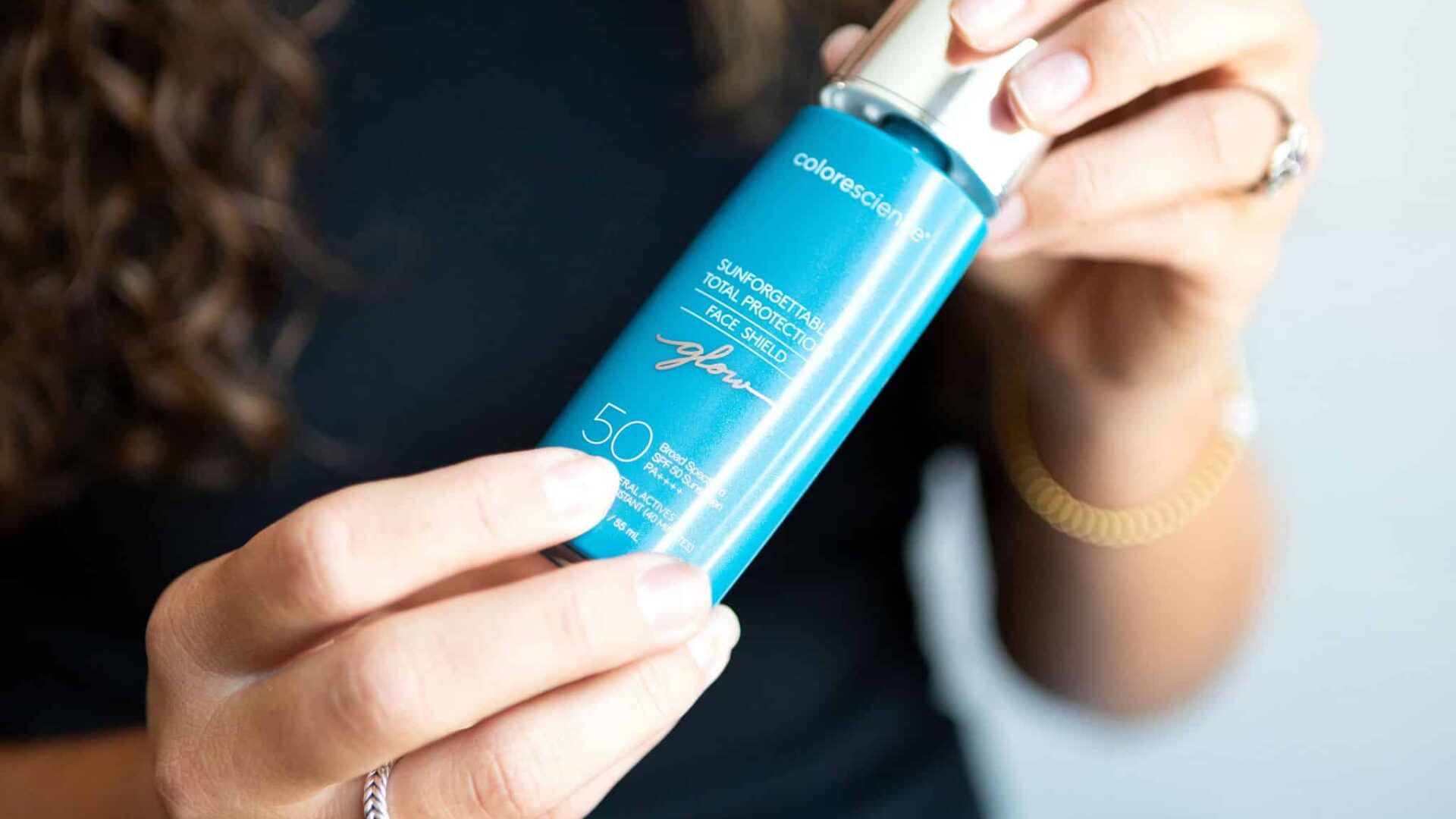 Woman holding sunscreen bottle, focusing on skin protection.