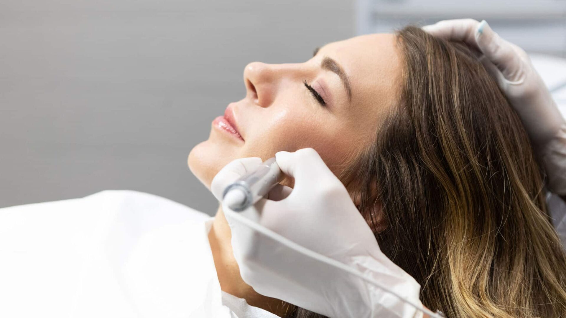 Woman undergoing cosmetic dermatology treatment at a clinic.